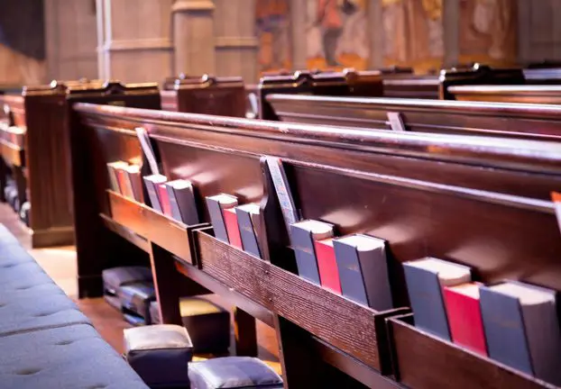 A row of pews with books in them.