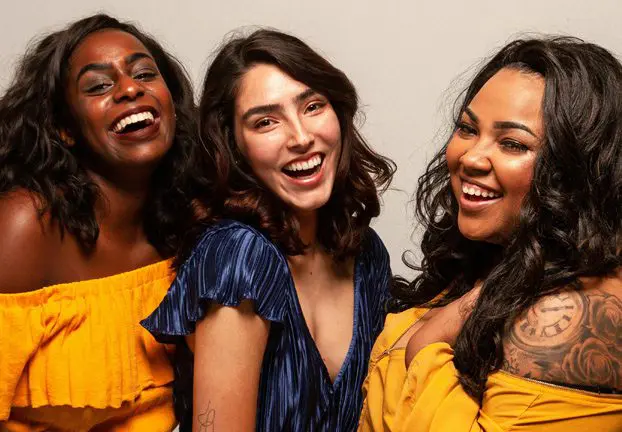 Three women in yellow dresses smiling for the camera.