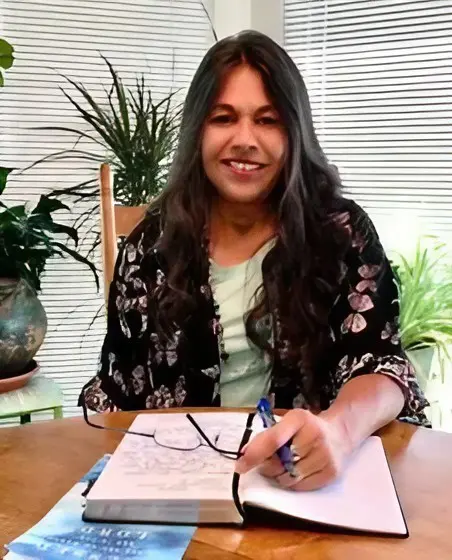 A woman sitting at a table with a pen and paper.