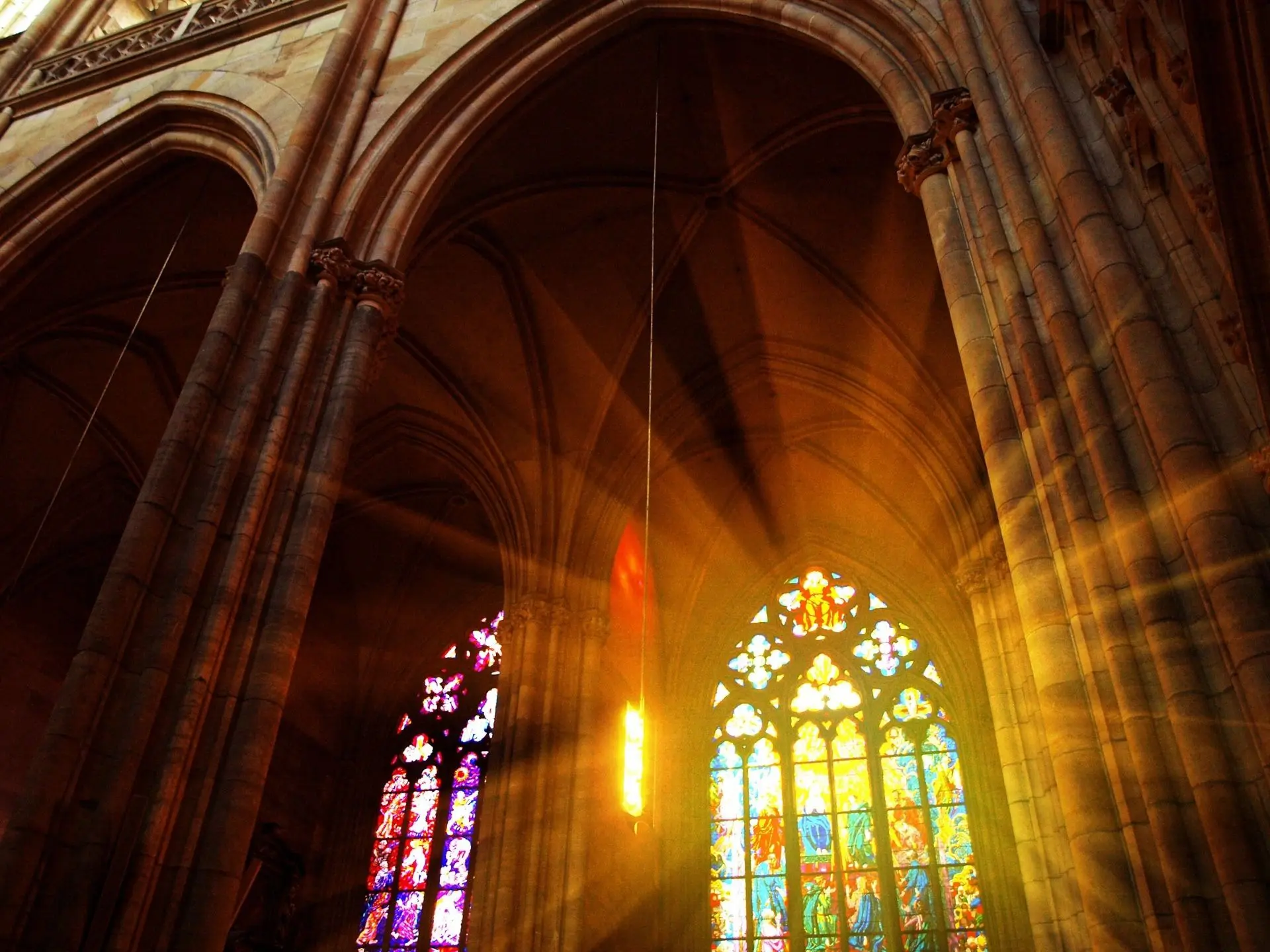 A cathedral with stained glass windows and sunlight coming through the window.