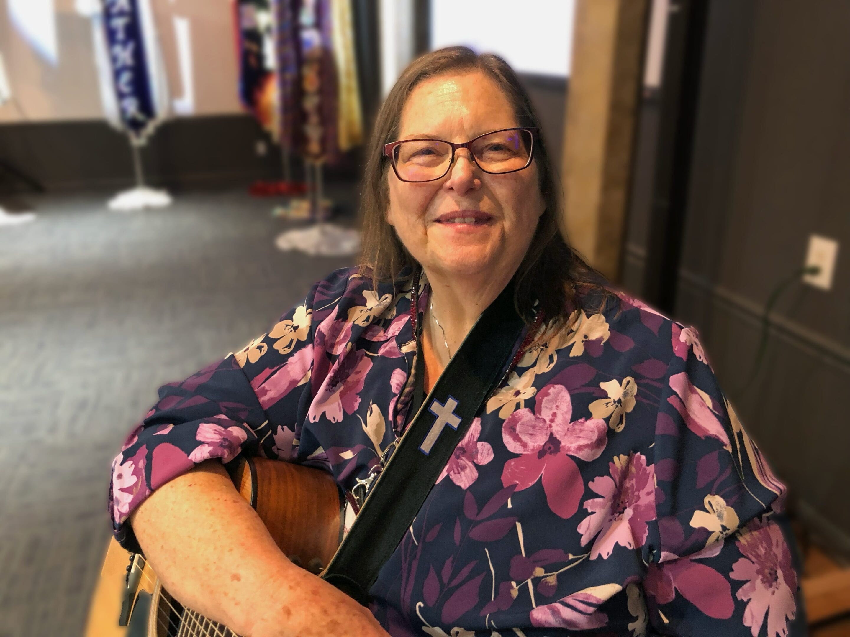 A woman sitting down with a guitar in her lap.