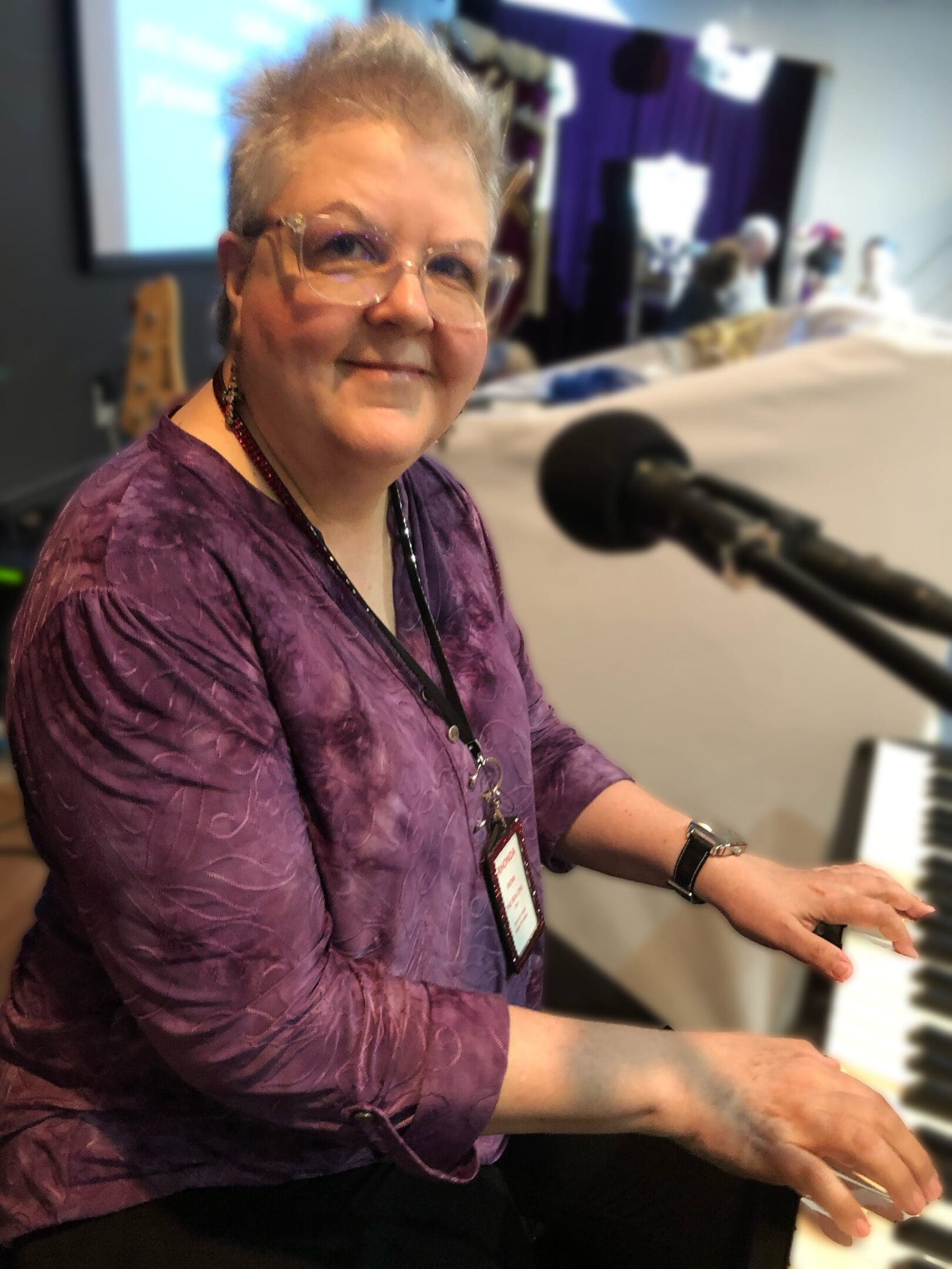 A woman sitting at the piano in front of a microphone.