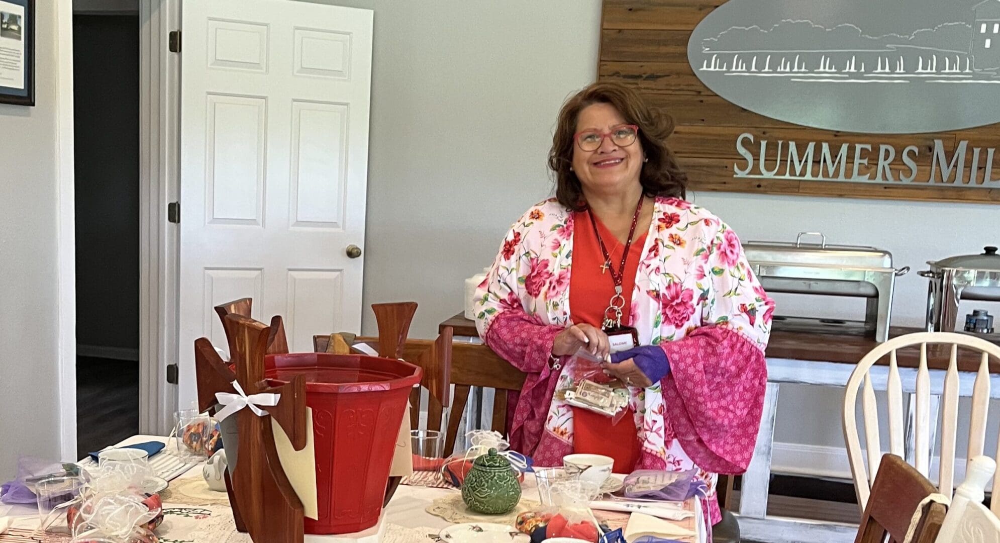 A woman standing in front of a table with many items on it.