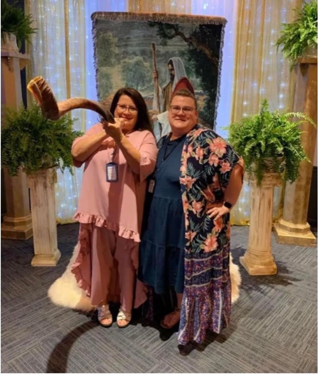 Two women posing for a picture in front of pillars.