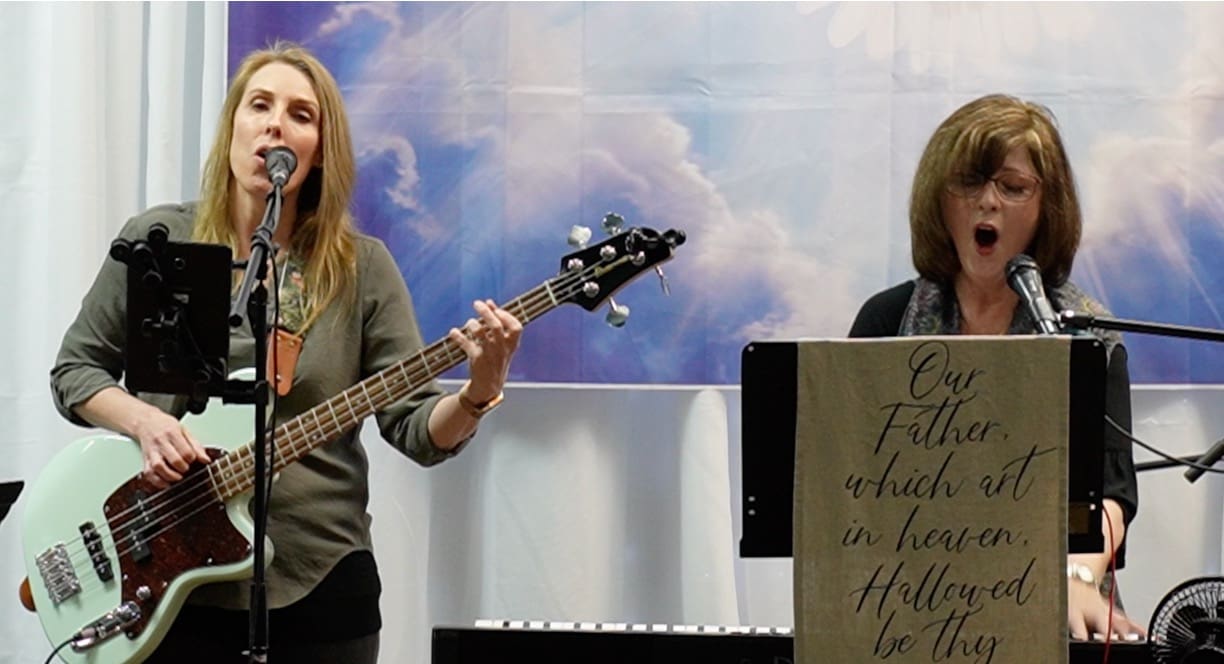 A woman playing an instrument while another person watches.