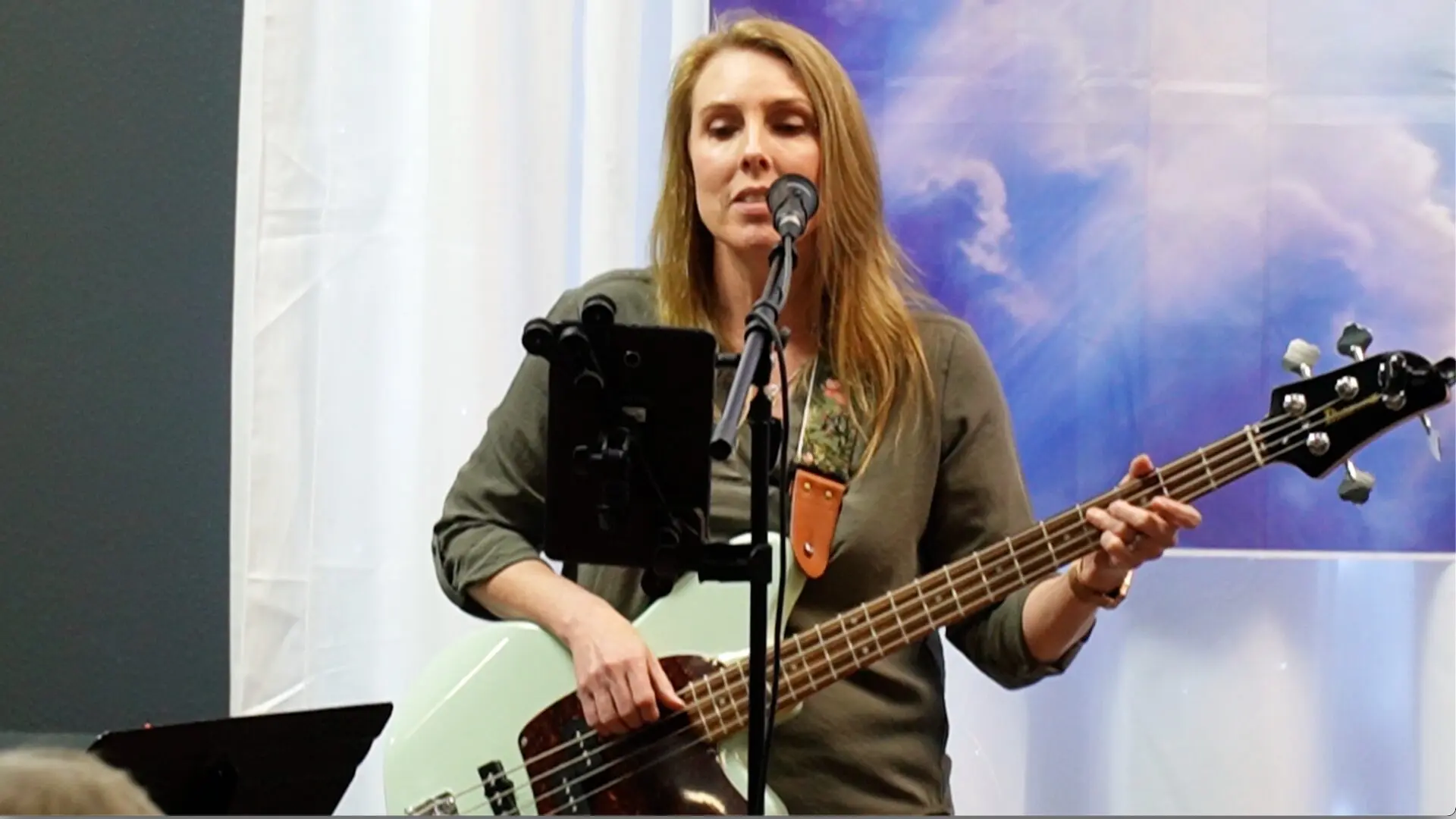 A woman holding a guitar and singing into a microphone.