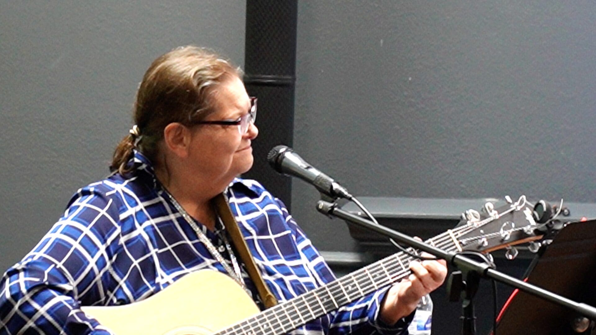 A woman sitting at a microphone playing an instrument.