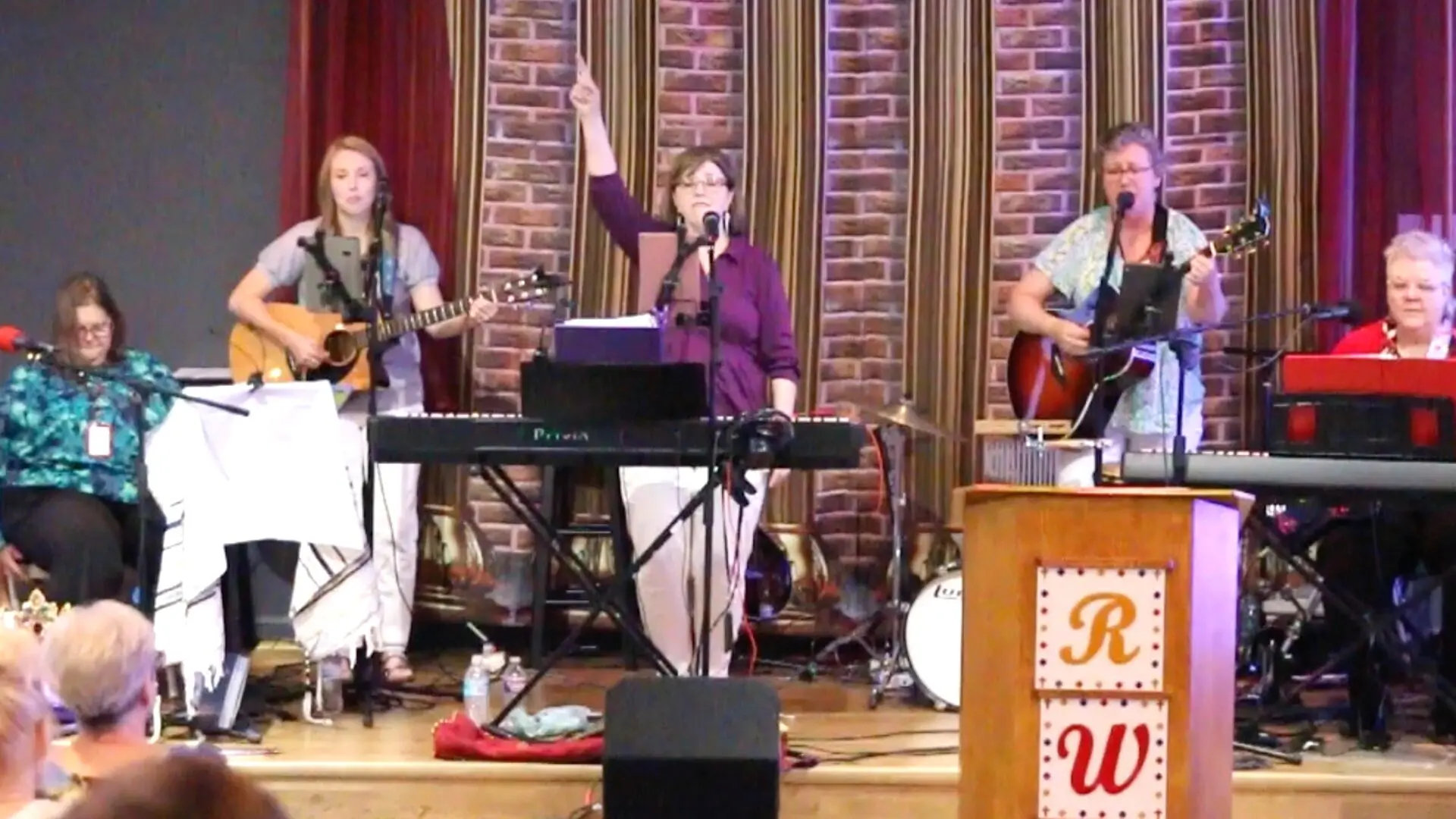 A group of people on stage singing and playing instruments.