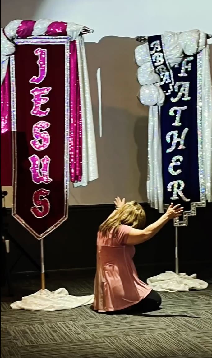 A woman is standing next to two banners.