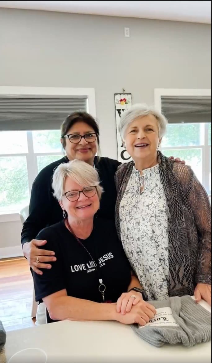 Three women pose for a picture in the living room.