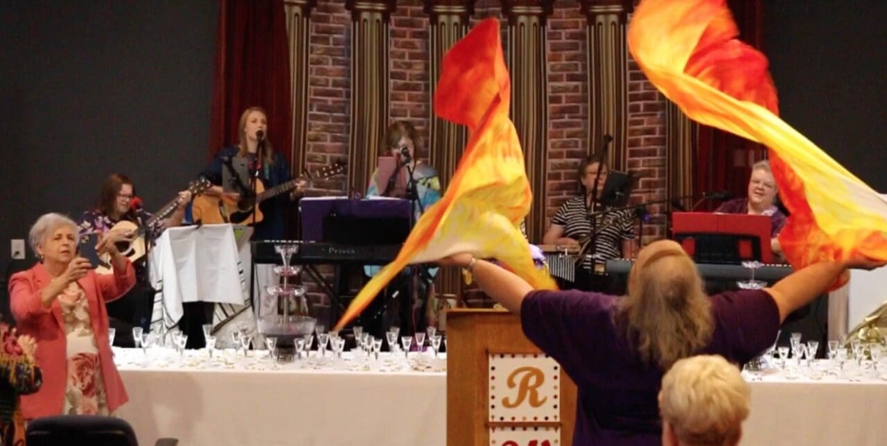 A woman holding up an orange and yellow flag.