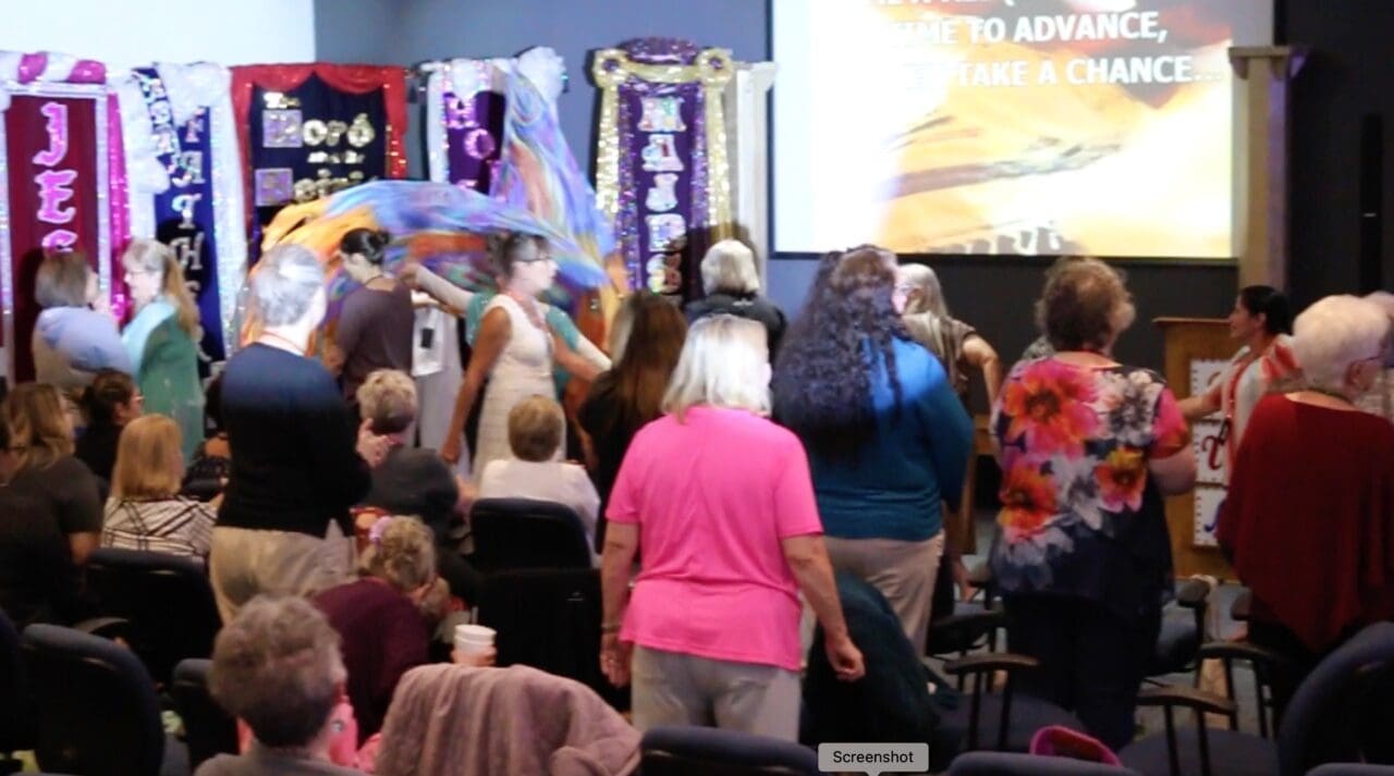 A group of people standing around in front of a screen.