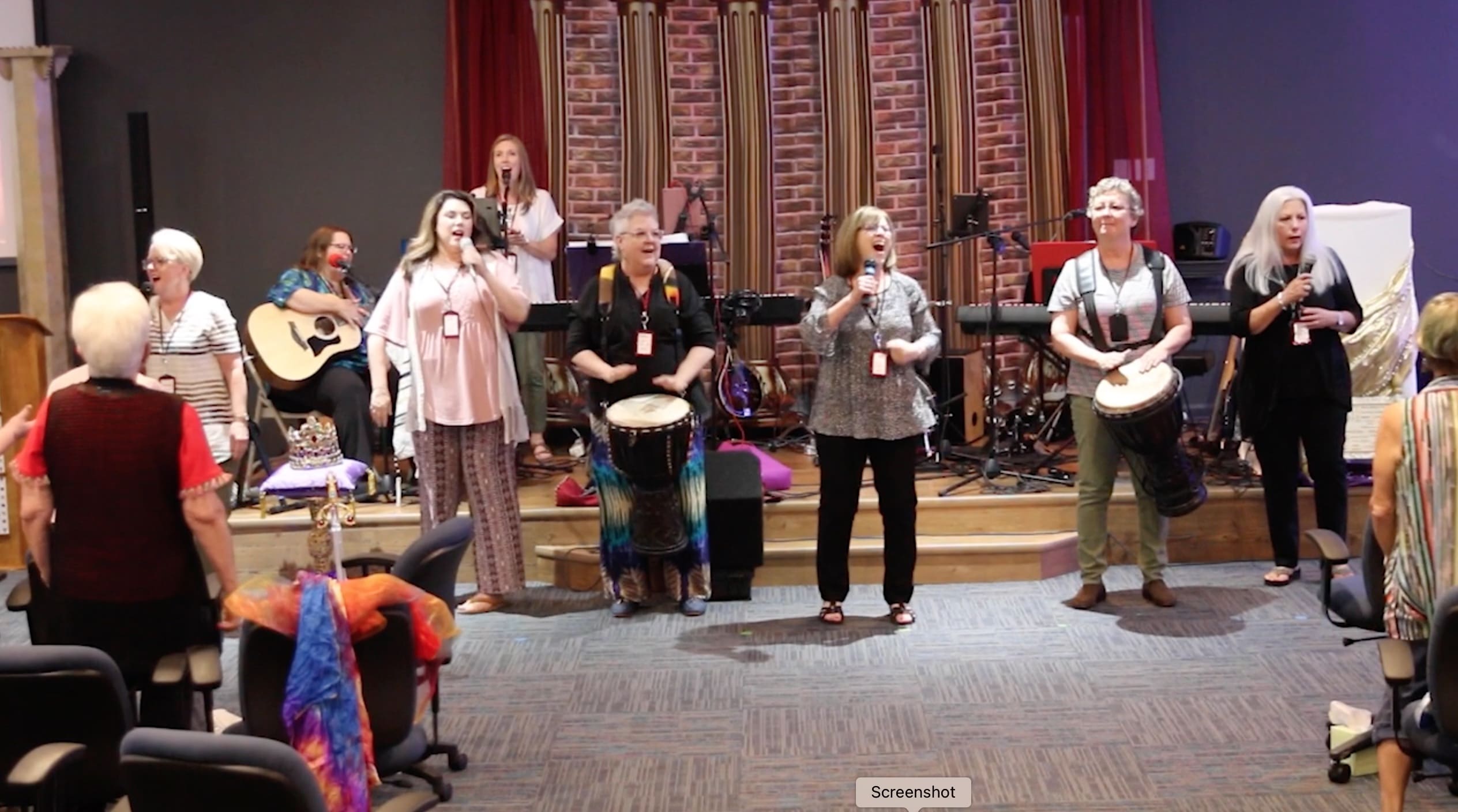 A group of people standing on stage holding drums.