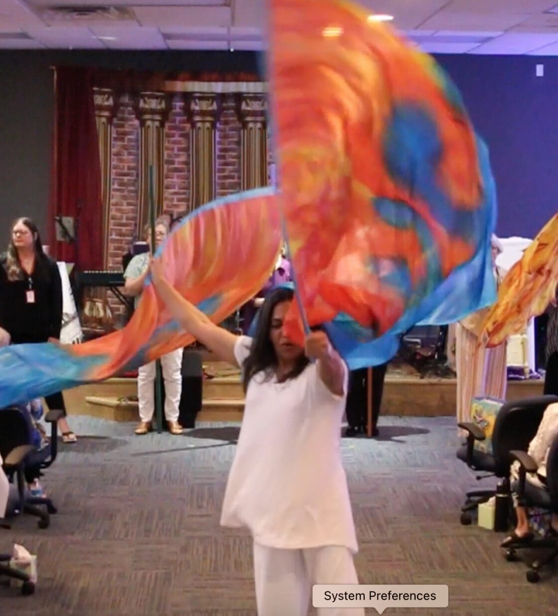 A woman in white dress holding up a colorful flag.