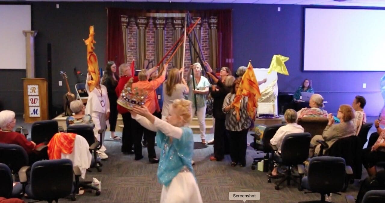 A group of people dancing in front of a wall.