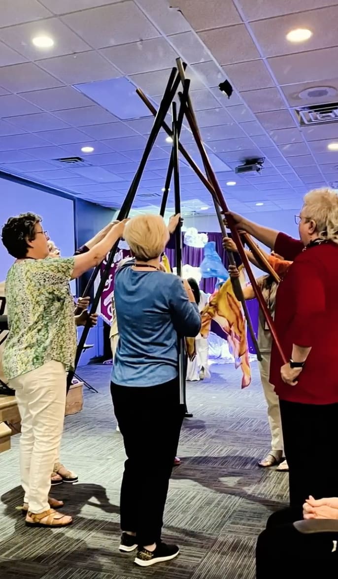 Three women are holding a flag on a pole.