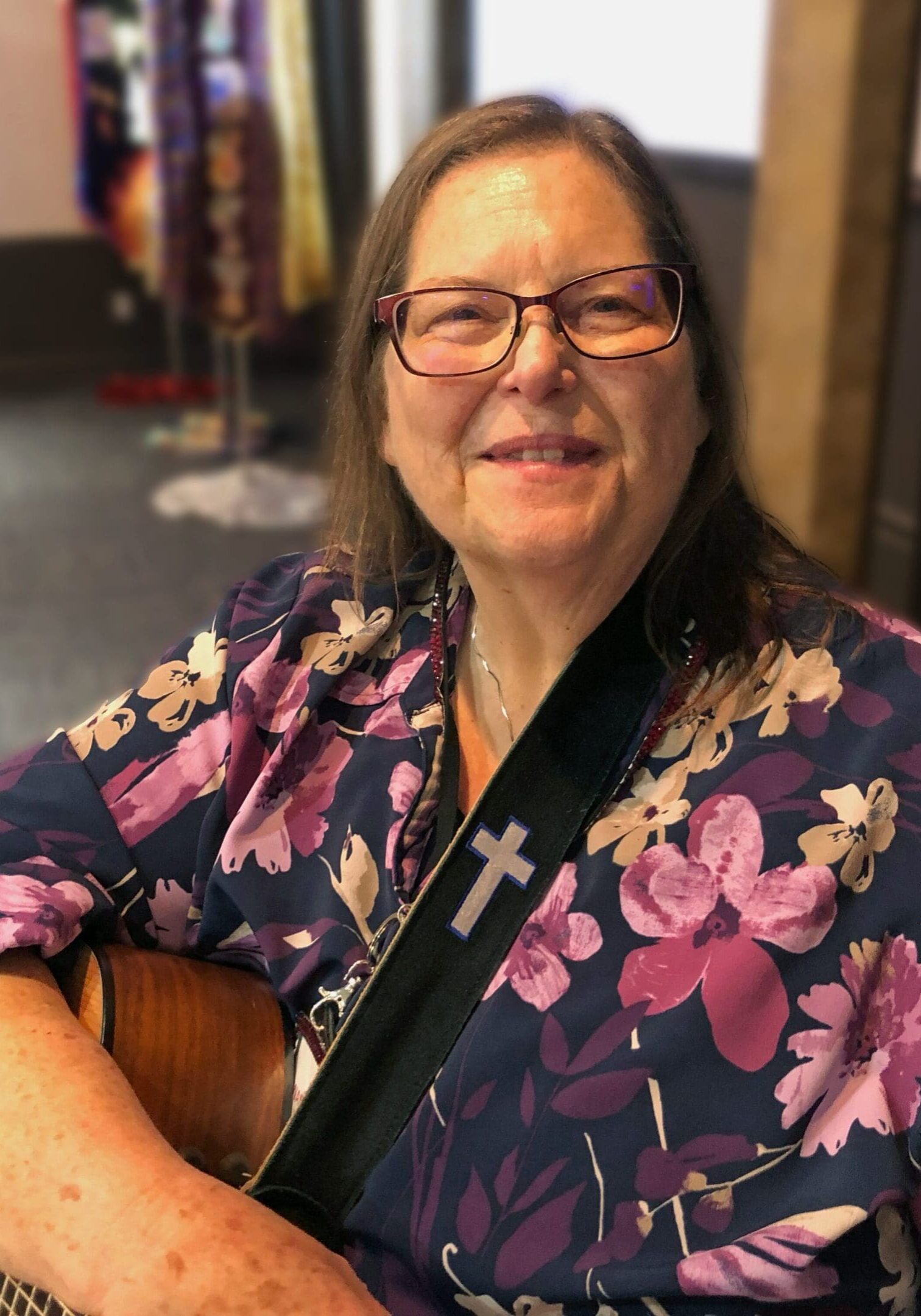 A woman sitting down with a guitar in her lap.