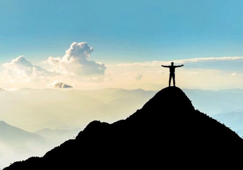 A person standing on top of a mountain with arms outstretched.