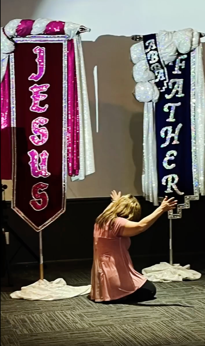 rwmi screen 17 - praying in front of banners